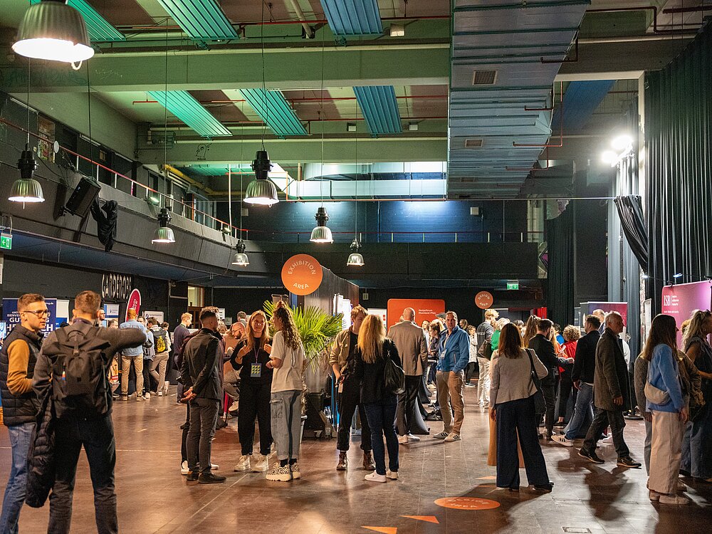 Besucherinnen und Besucher unterhalten sich beim Networking in entspannter, lockerer Atmosphäre.